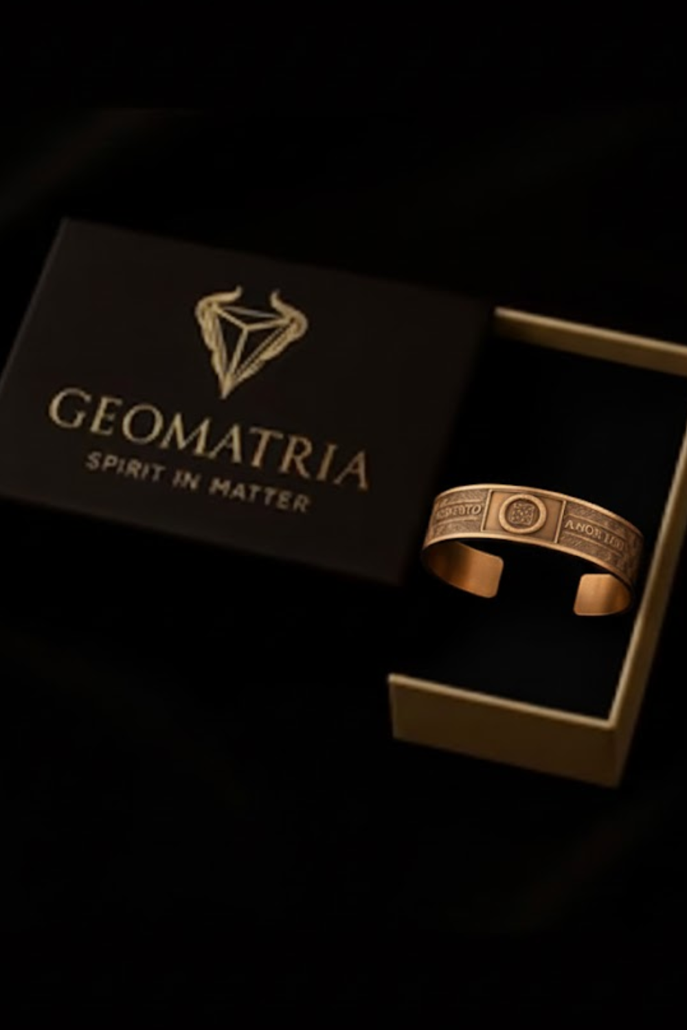 A gold-colored bracelet is displayed inside a black box with the word "Geomatria" printed on it.
