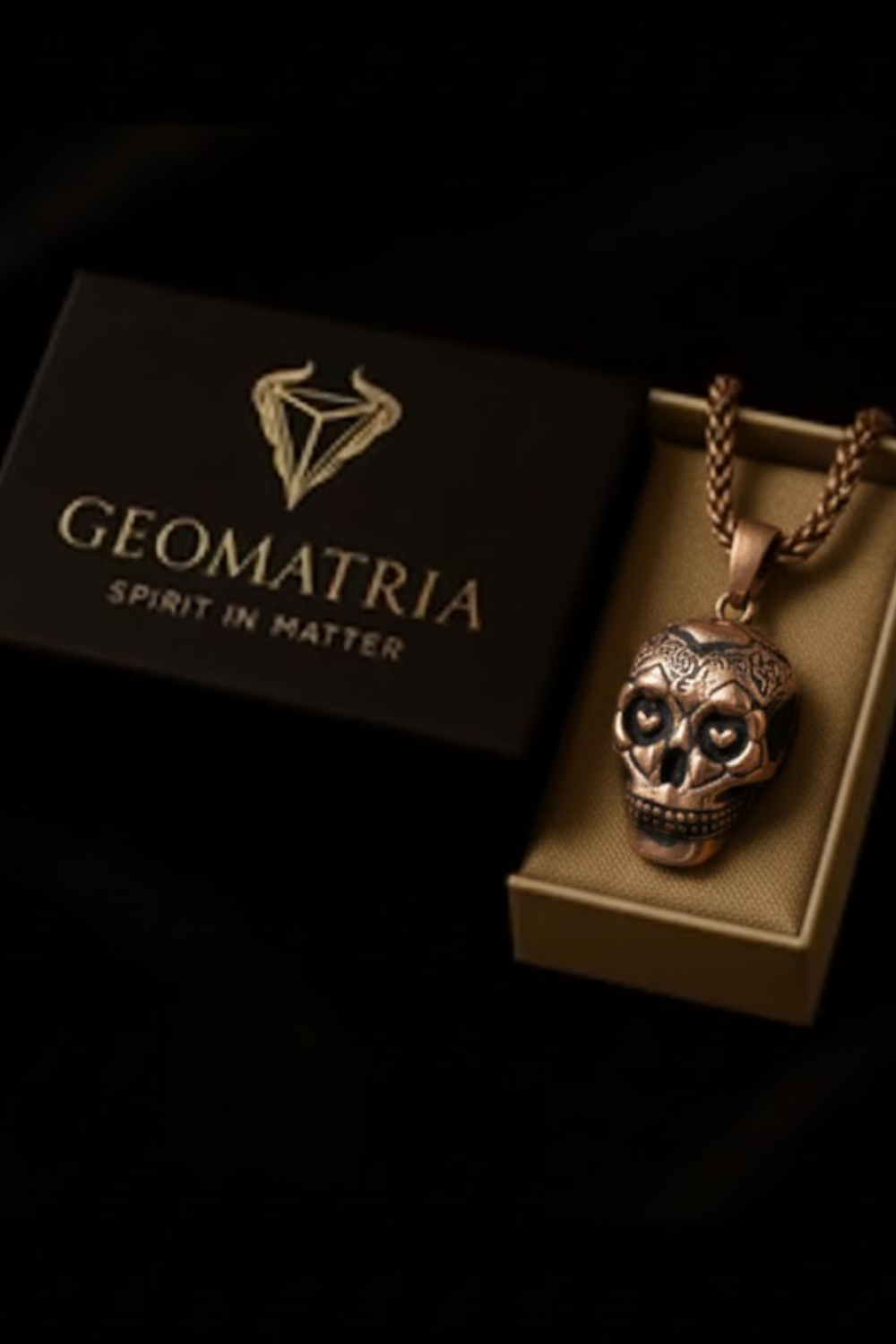 a pendant necklace with a skull pendant, displayed in a box with the brand name "Geomatria" written on it.