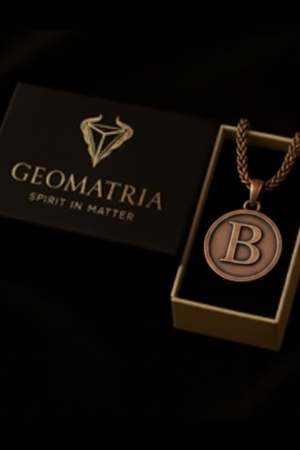 a necklace with a pendant, placed inside a box with the word "Geomatria" written on it.