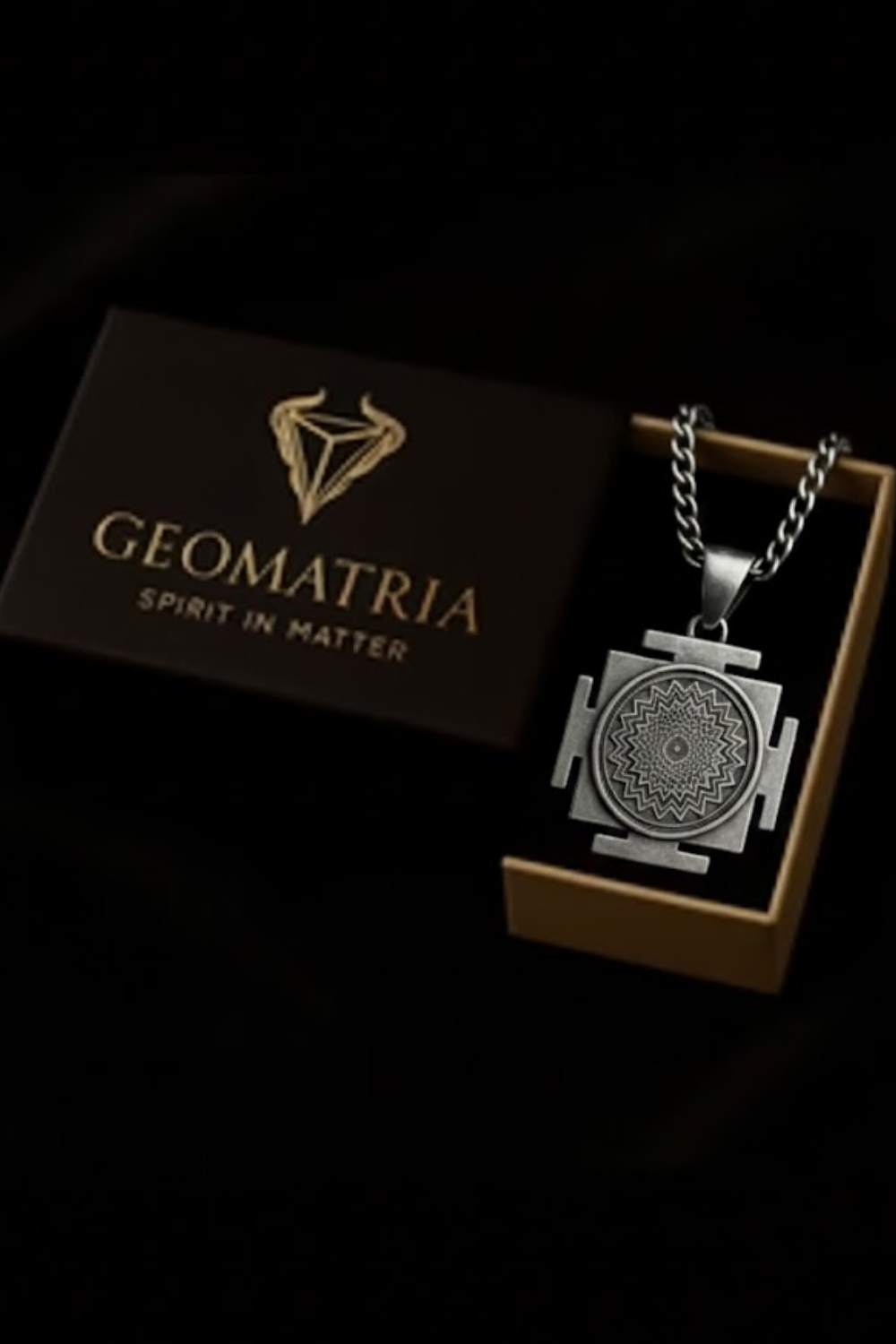 a necklace with a pendant, placed inside a brown box with the word "Geomatria" written on it.