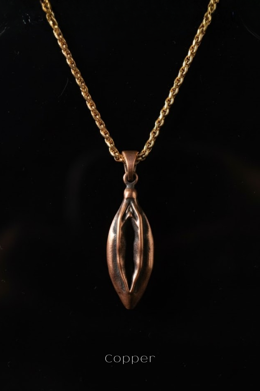 A copper-colored pendant necklace with a chain is displayed against a black background.
