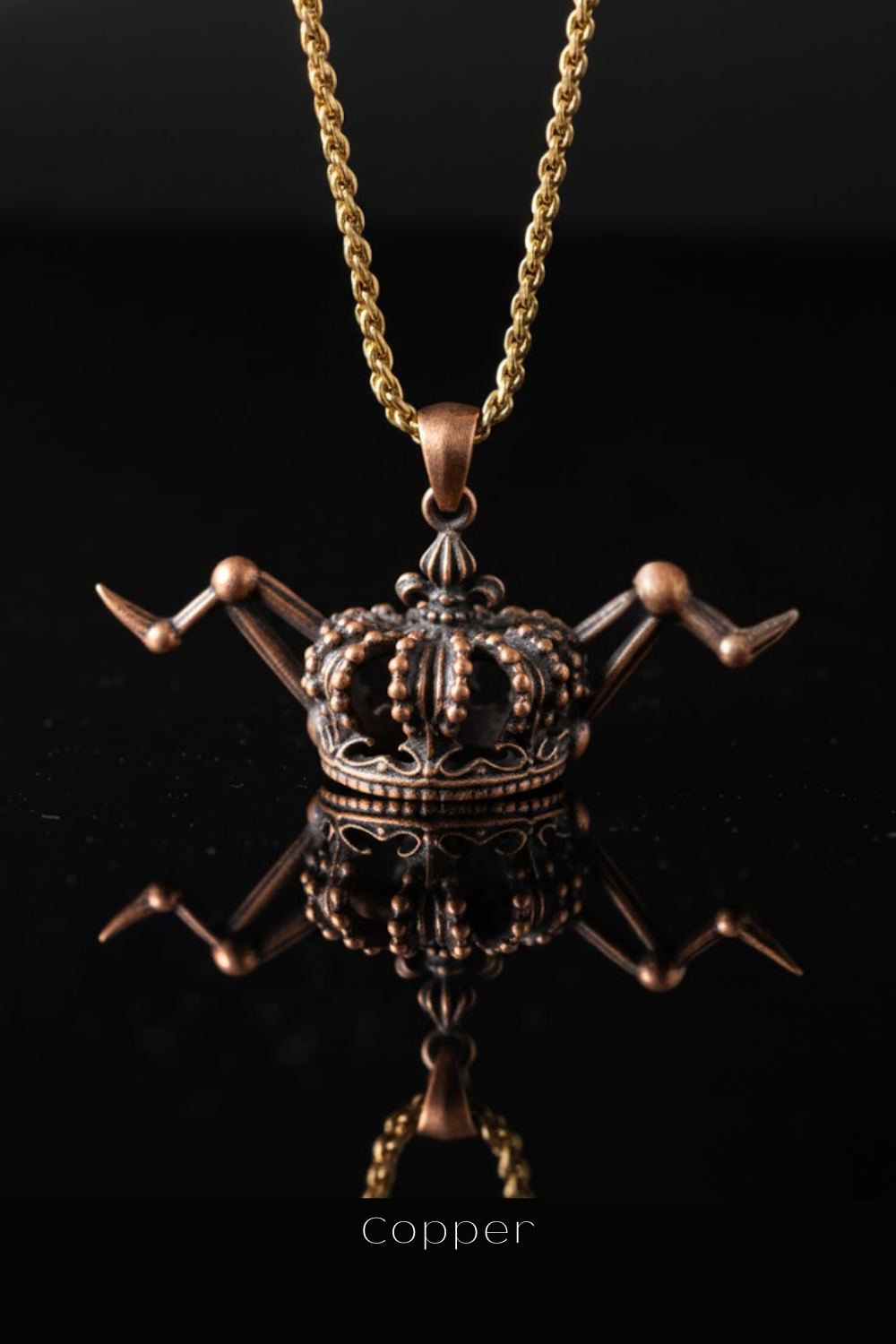 A copper-colored pendant necklace with a crown-like design, suspended from a chain against a black background.