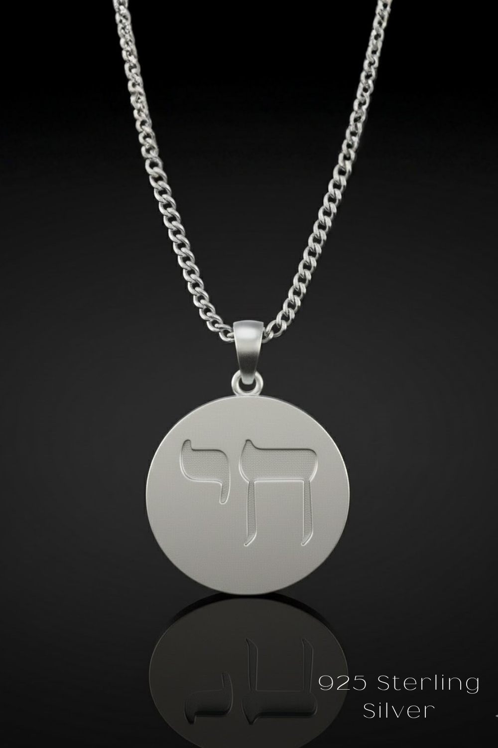 A silver necklace with a circular pendant featuring a symbol, possibly a Hebrew letter or symbol, against a black background.