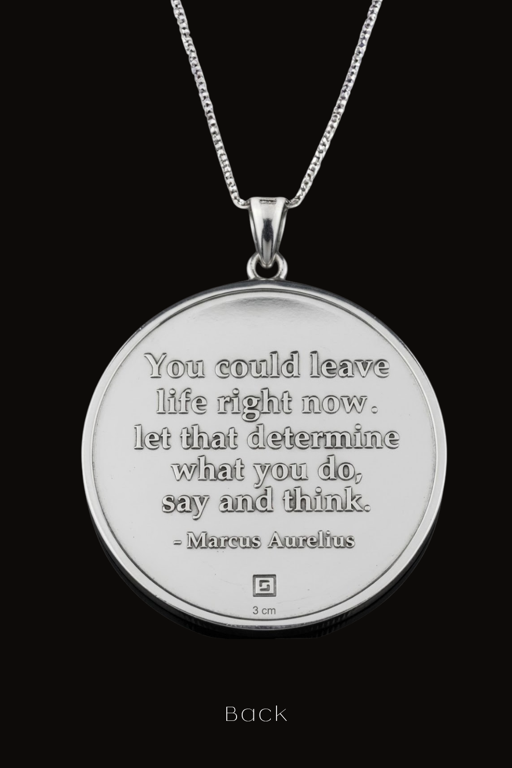 A silver-colored pendant necklace with a circular medallion featuring a quote by Marcus Aurelius.