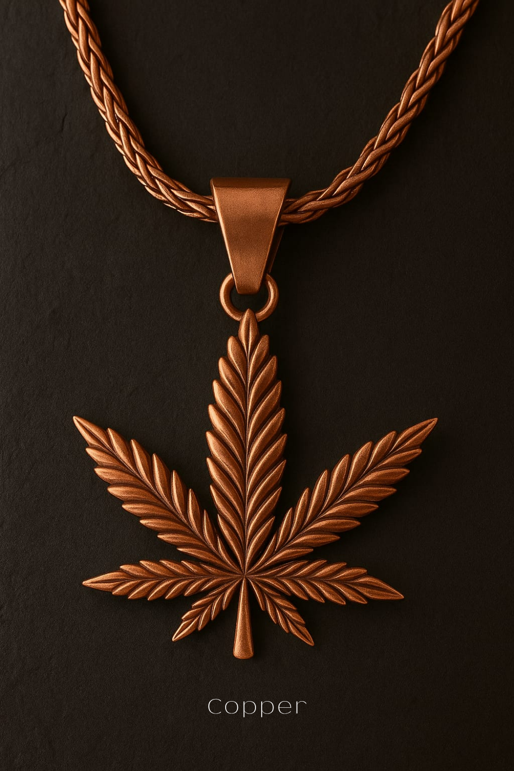 A copper-colored pendant in the shape of a marijuana leaf, suspended from a chain against a dark background.