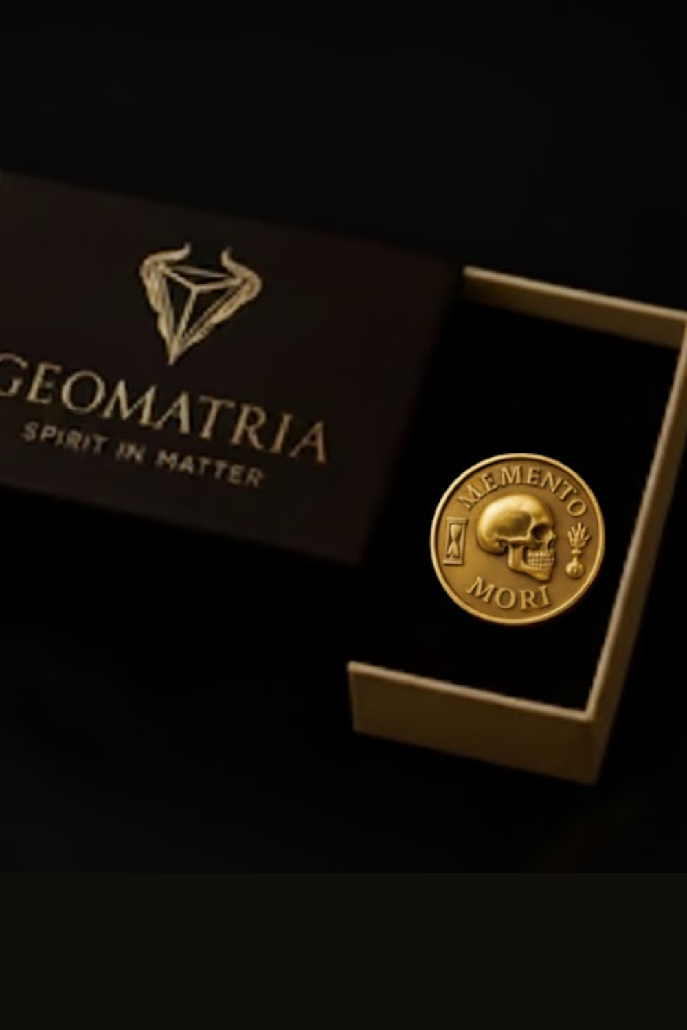 a gold-colored coin with a skull and crossbones symbol, placed inside a black box with the word "Geomatria" printed on it.
