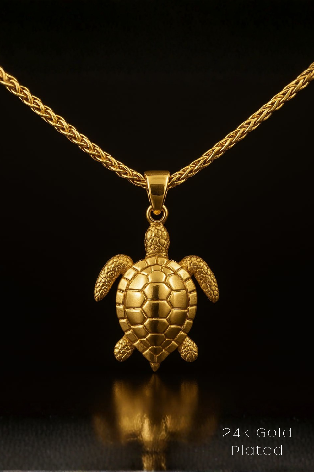 A 24k gold plated pendant in the shape of a turtle is displayed against a black background.
