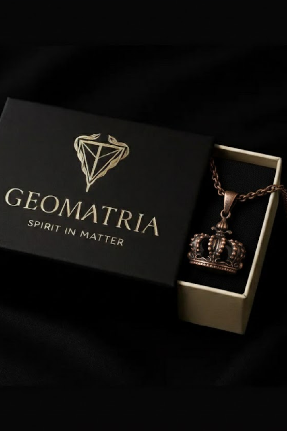 A black jewelry box with a gold-colored logo and the text "Geomatria" on it, along with a necklace pendant inside the box.