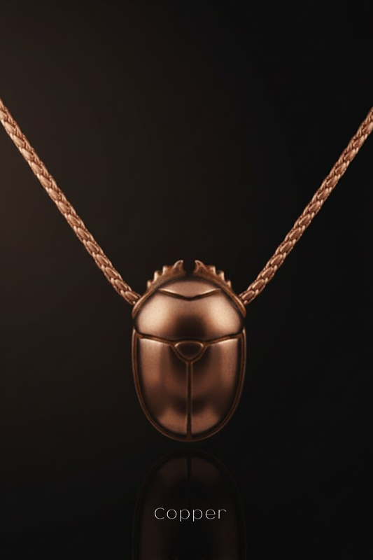 A copper-colored pendant necklace with a detailed design, displayed against a dark background.