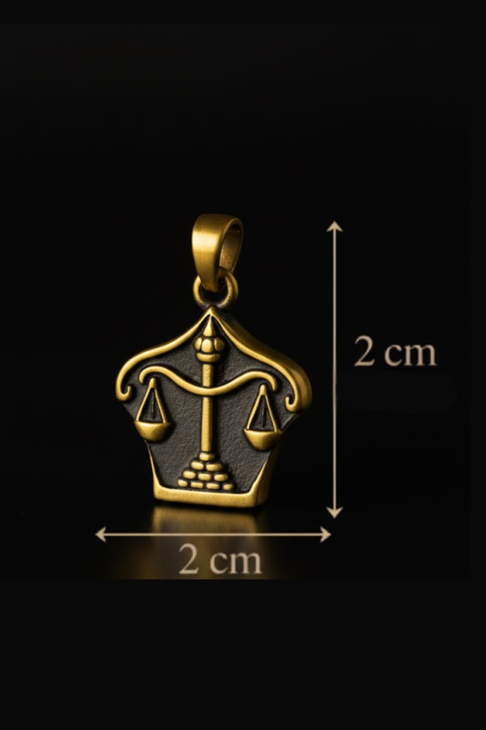 A gold-colored pendant in the shape of a scale, with a small figure of a person on one side and a weight on the other, against a black background.