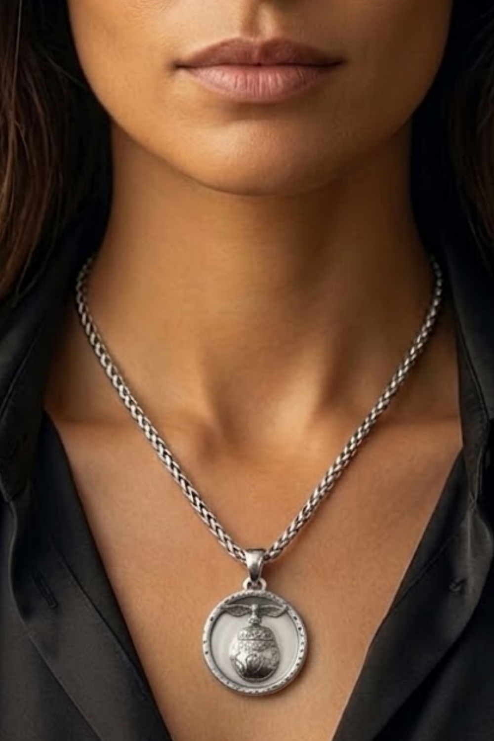 A close-up of a woman's neck and chest area, with a silver necklace featuring a pendant hanging around her neck.