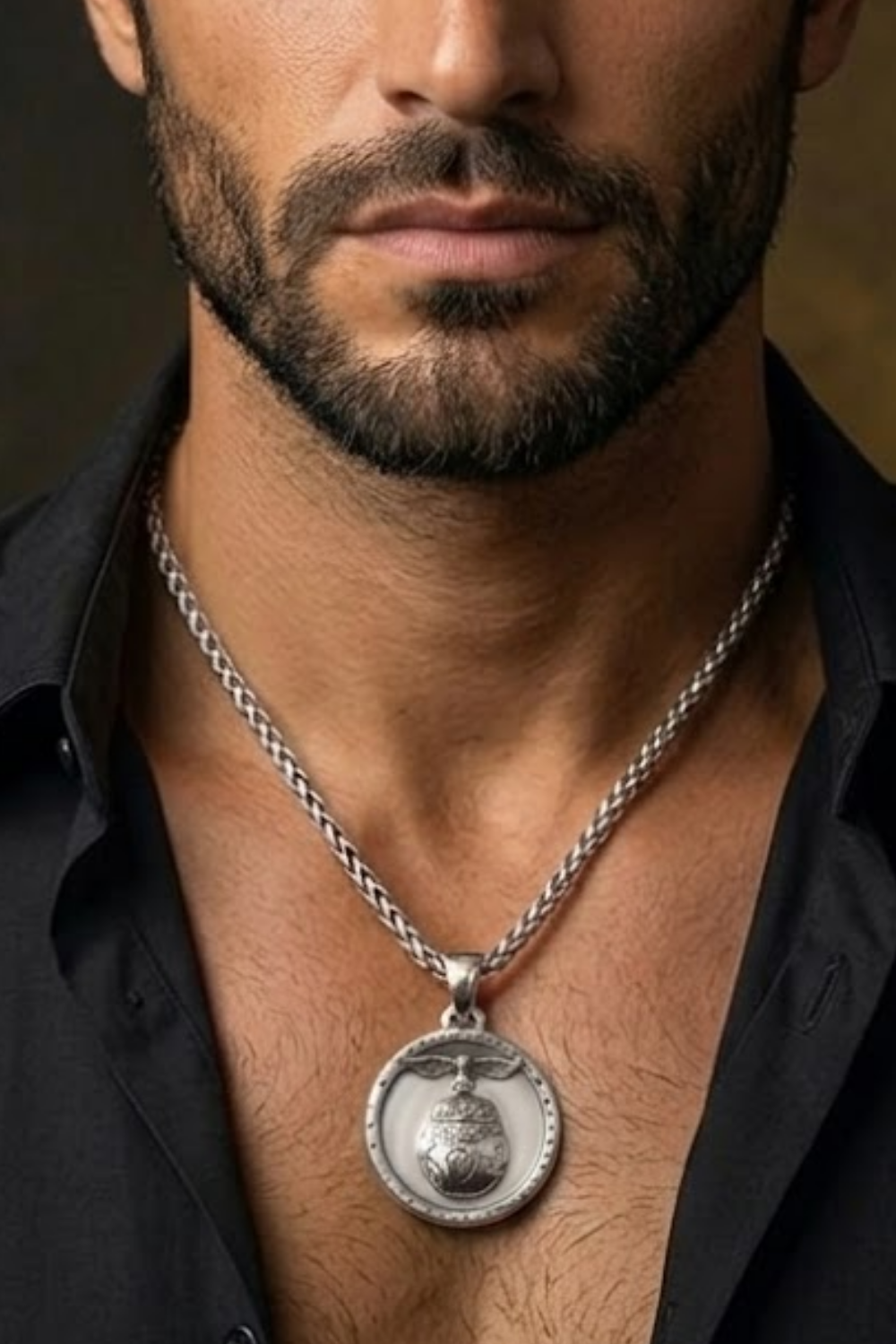 A close-up of a man's neck and chest area, with a silver necklace and a pendant visible.