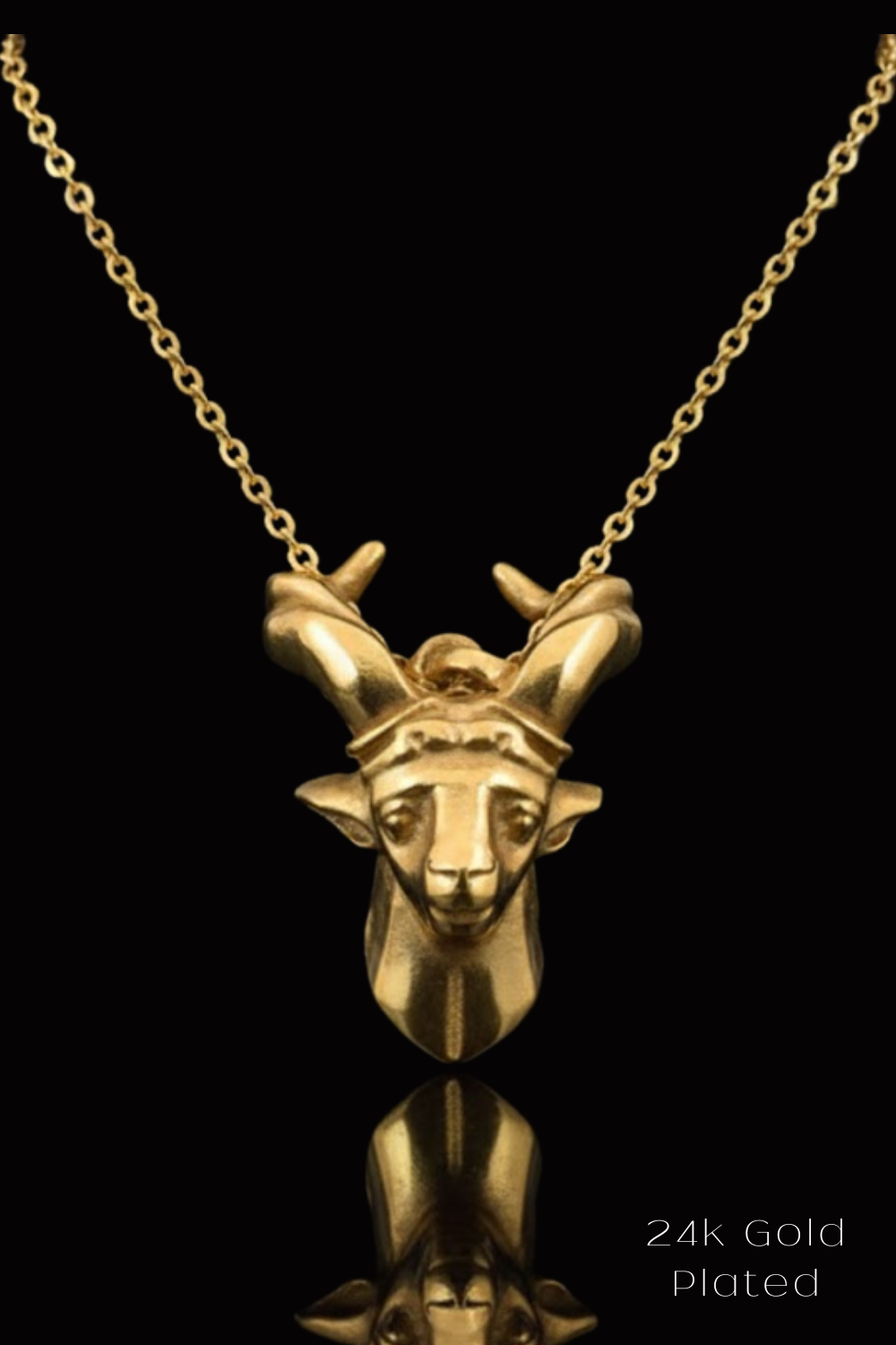 A 24k gold-plated pendant in the shape of a goat's head is displayed against a black background.