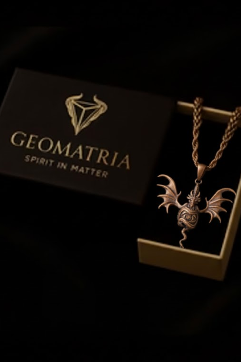a pendant with a dragon design, displayed in a box with the text "Geomatria Spirit in Matter" printed on it.