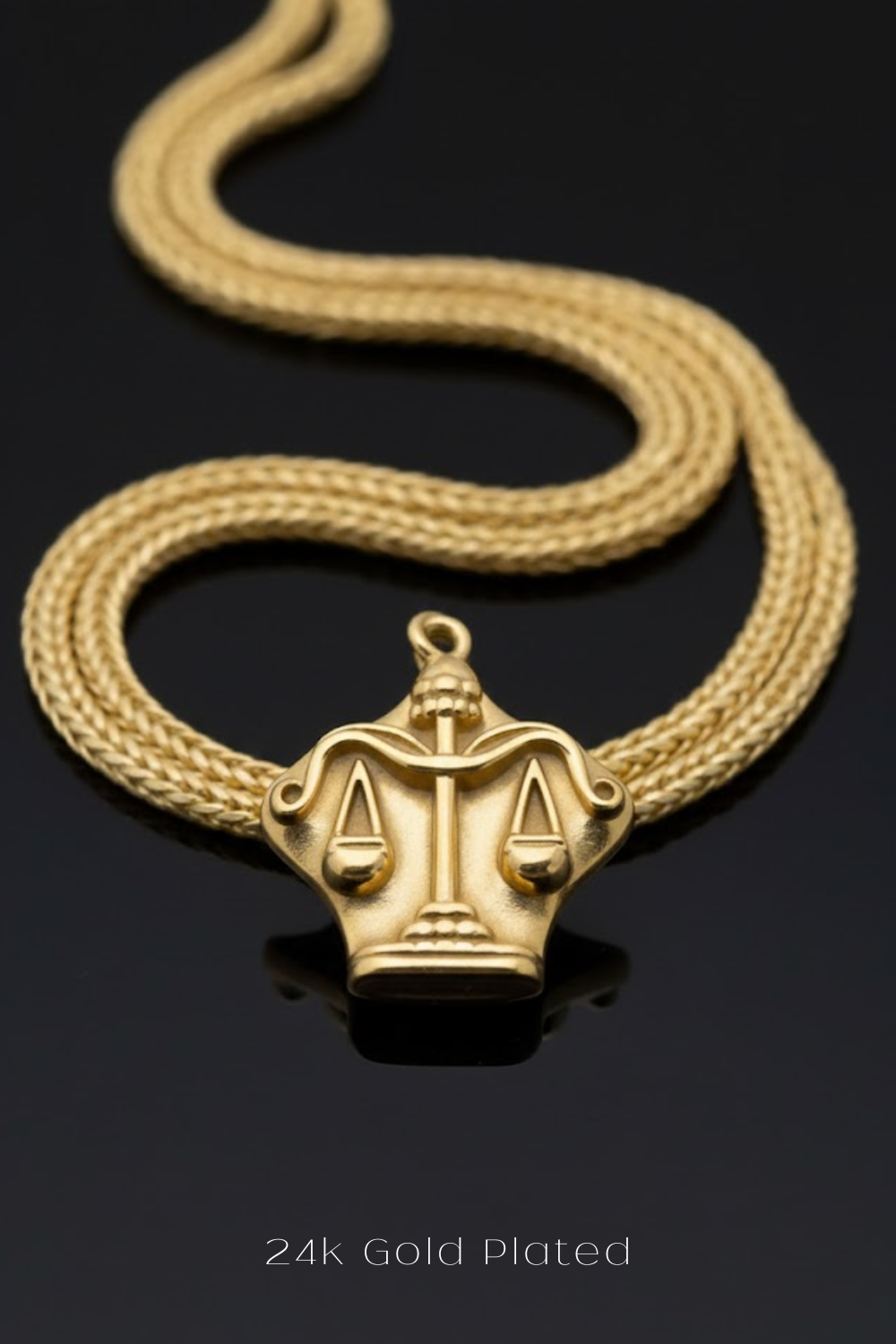 A gold-plated necklace with a pendant featuring a design of scales and a lion's head.