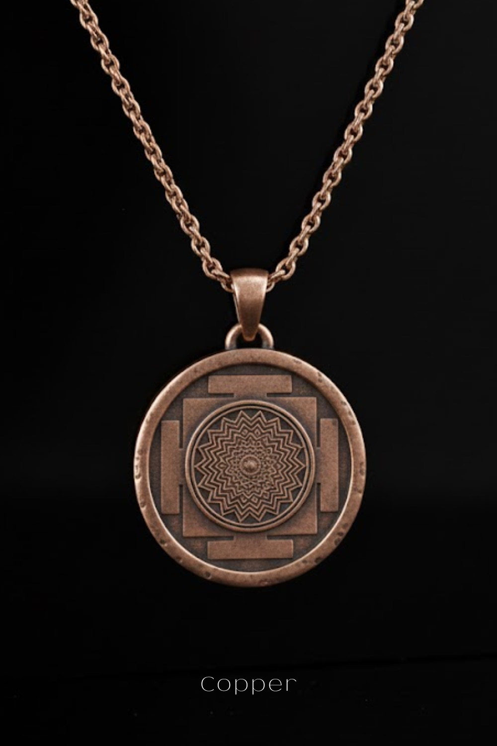 A copper-colored pendant necklace with a circular medallion featuring a mandala design.
