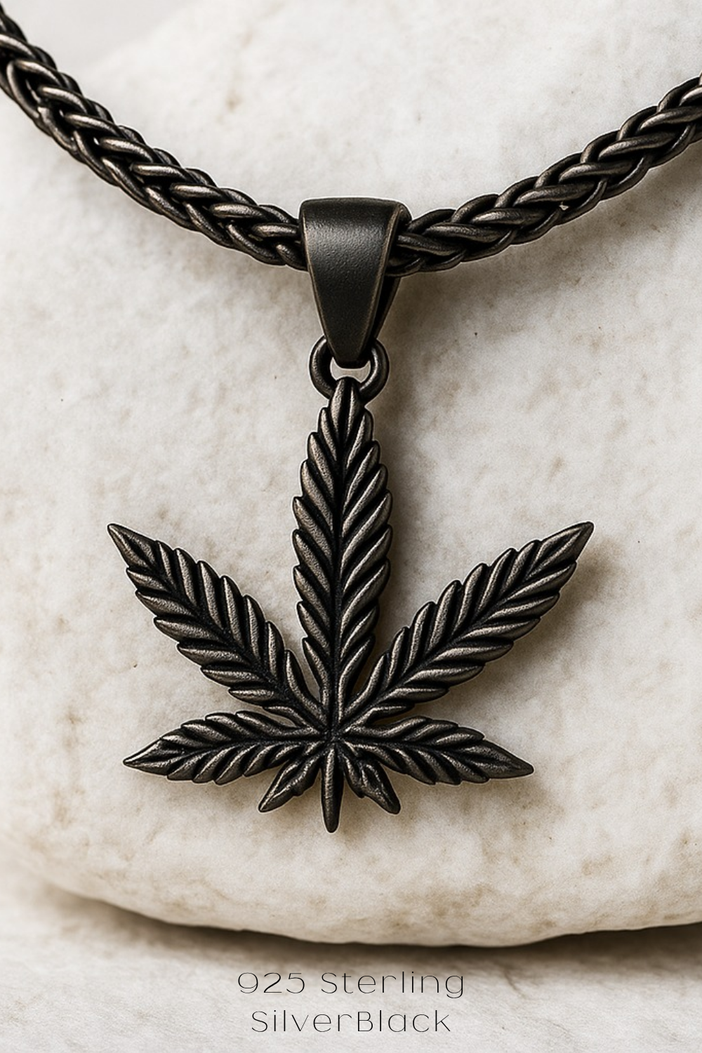 A silver-colored pendant necklace with a black leaf-shaped pendant in the center.