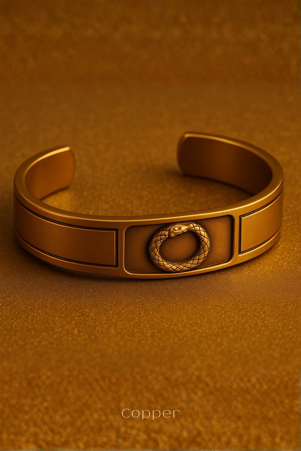 A gold-colored bracelet with a snake design on the front, resting on a textured surface.