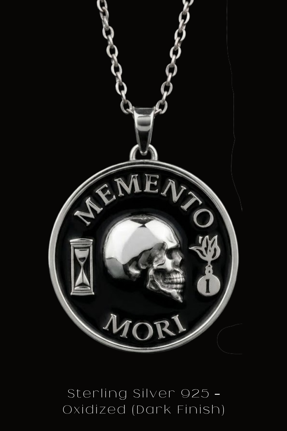 a silver necklace pendant with a skull design and the Latin phrase "Memento mori" (The Memory of Death) inscribed on it.