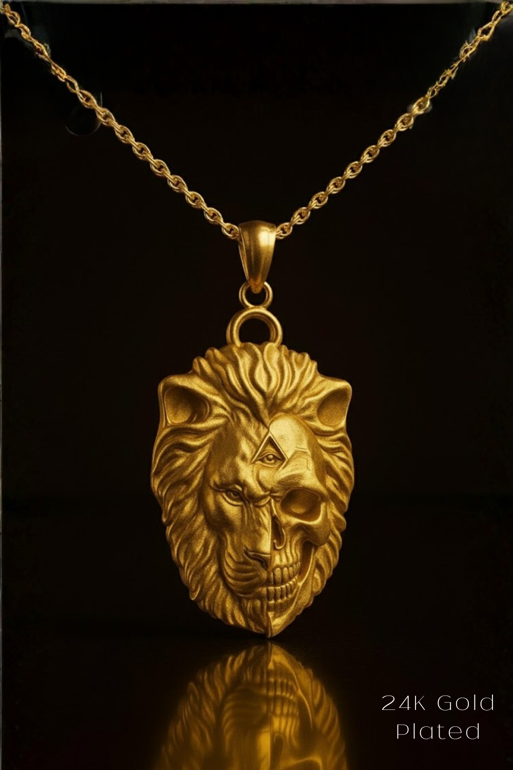 A gold-colored pendant necklace with a detailed lion's head design and a skull-like face, suspended from a chain against a black background.