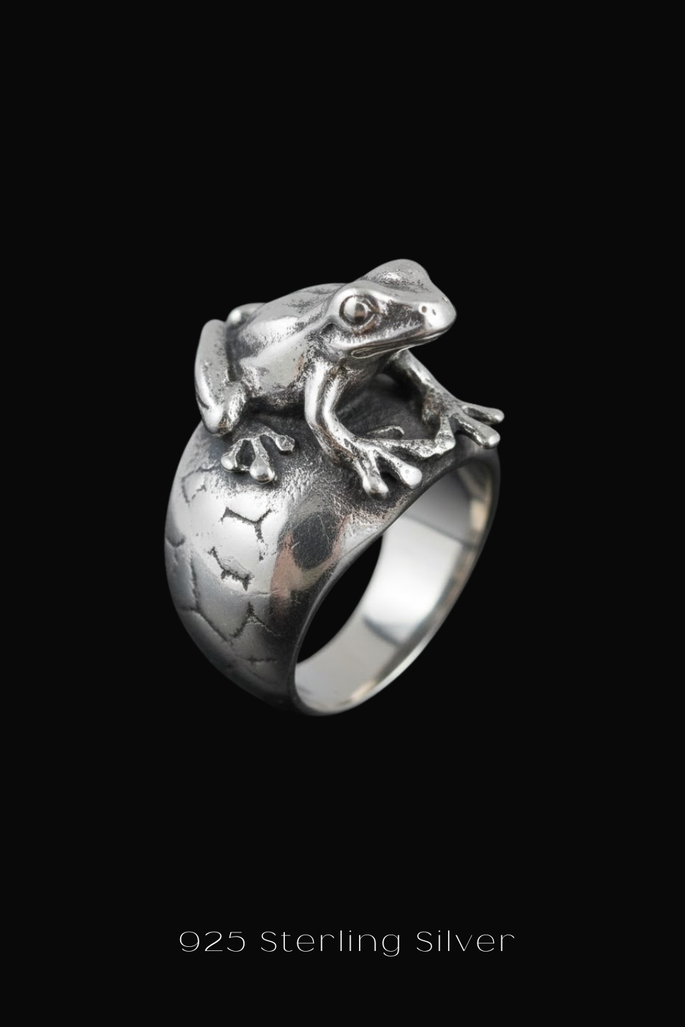 A silver ring with a detailed frog design on the band.