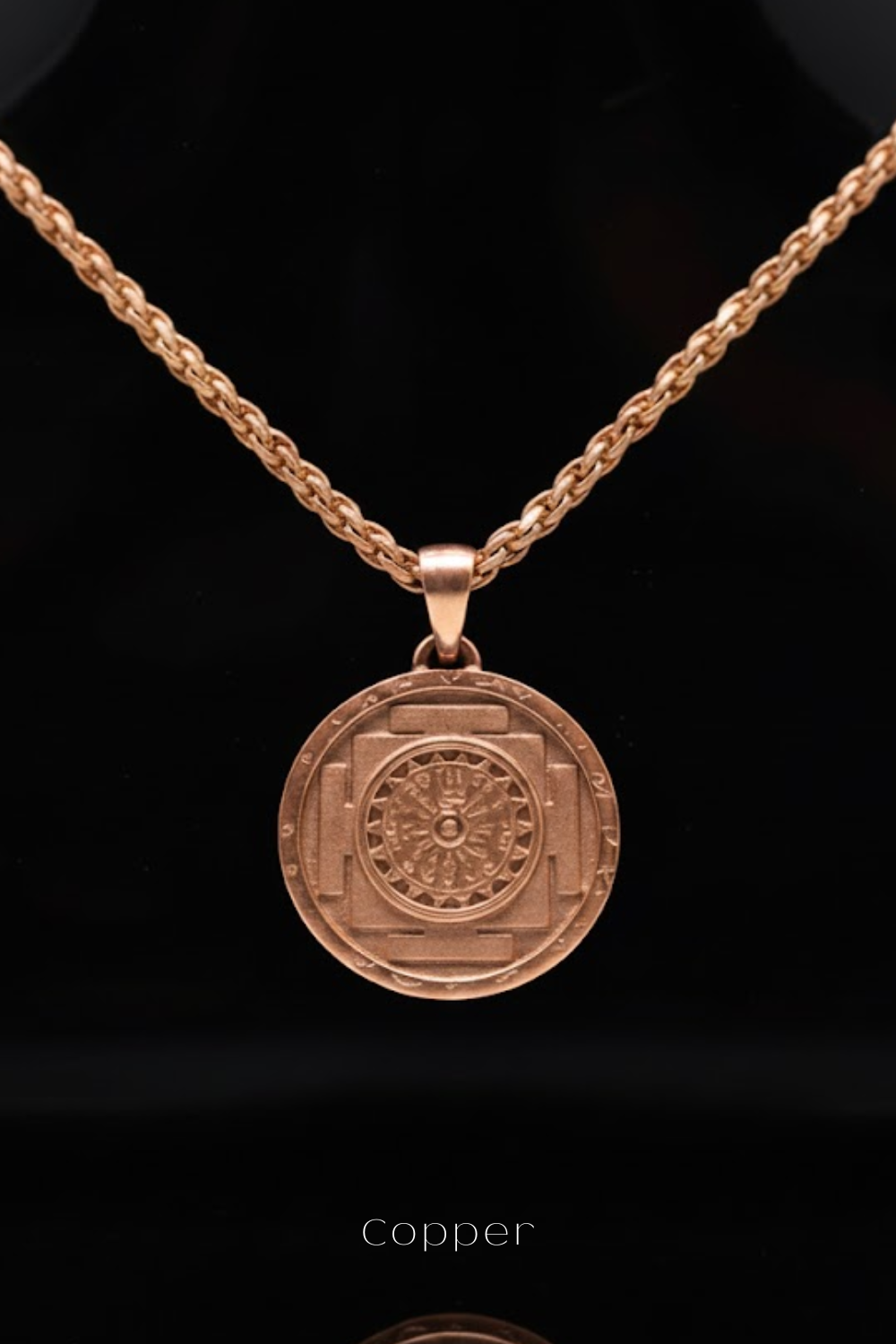 A copper-colored pendant necklace with a circular medallion featuring a detailed design.