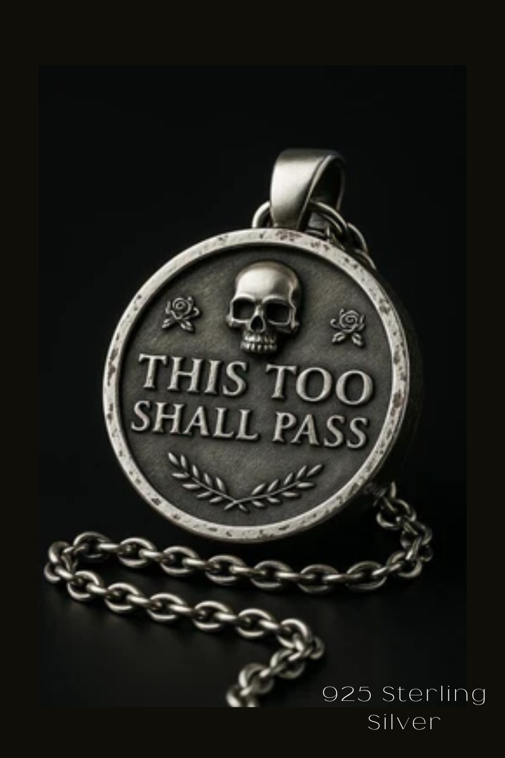 A silver-colored pendant with a skull and rose design, and the text "THIS TOO SHALL PASS" engraved on it.