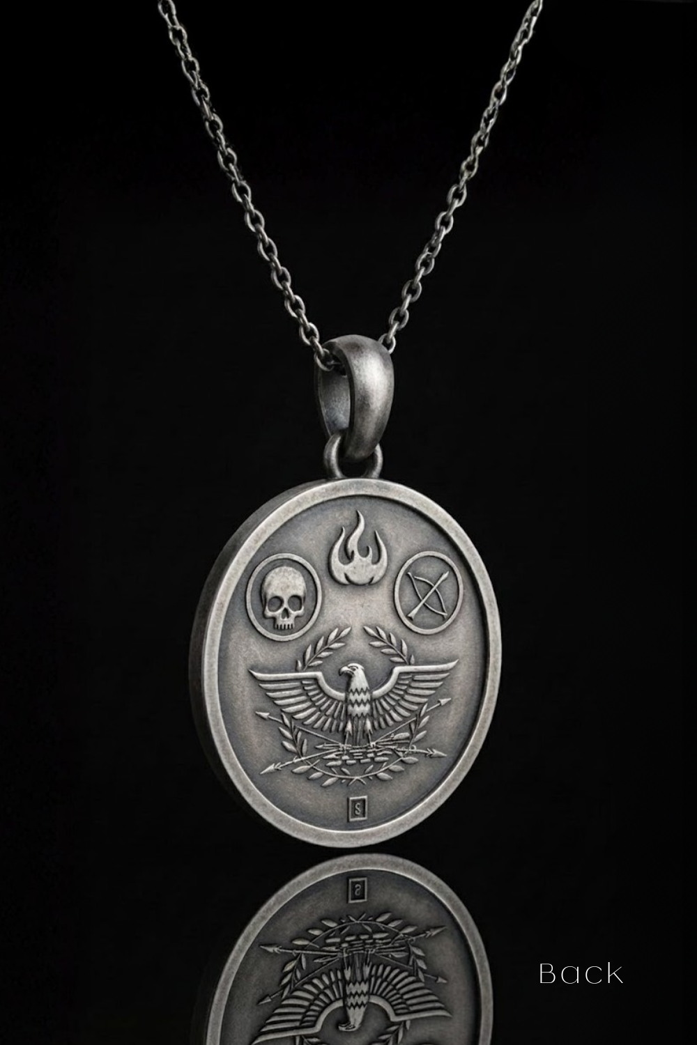 a silver-colored pendant necklace with a circular medallion-like design on it. The medallion has an eagle, skull, and cross symbol on it, and the pendant is suspended from a chain.