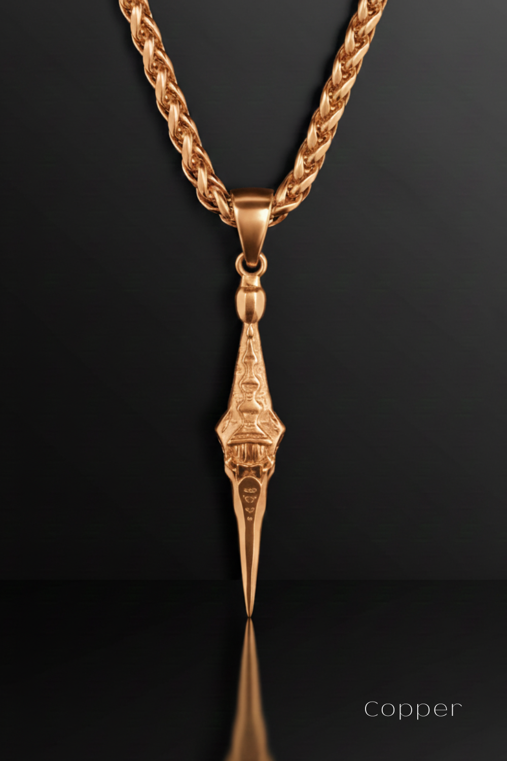 A gold-colored necklace with a pendant featuring an intricate design, displayed against a black background.