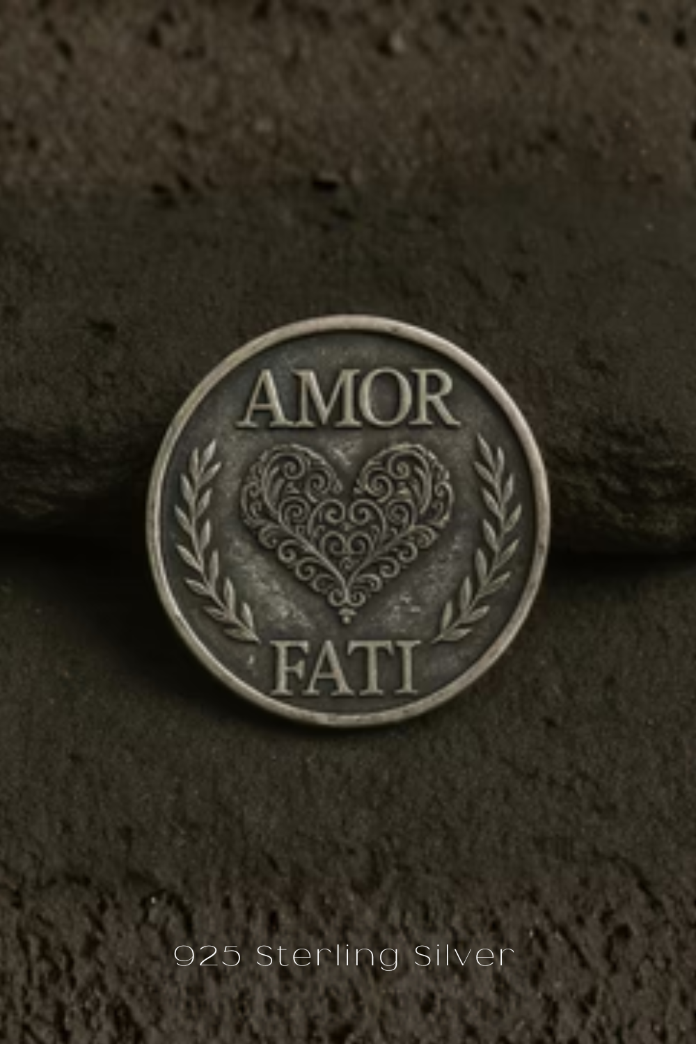 a close-up of a silver coin with a heart design and the words "Amor Fati" inscribed on it.