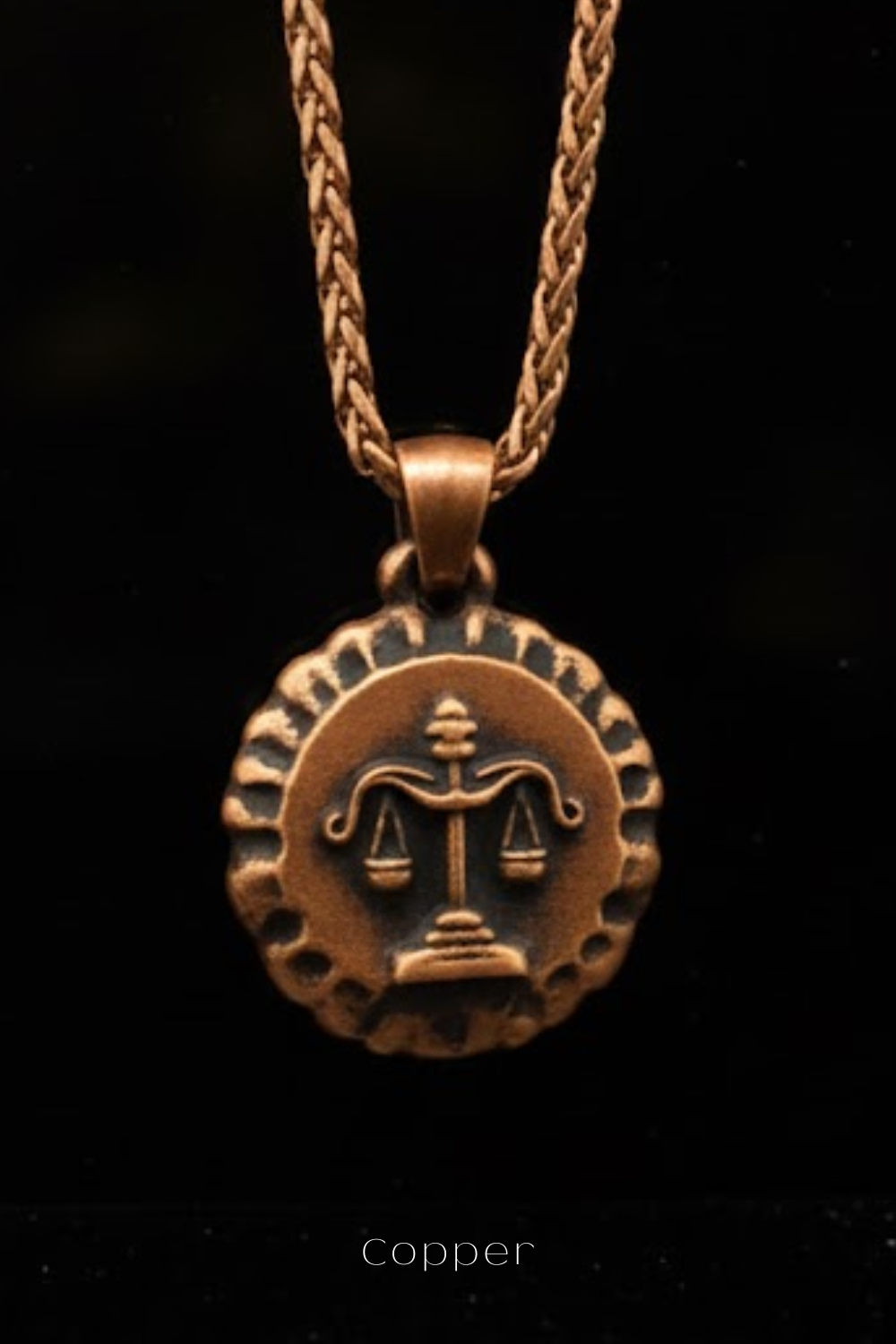 A copper-colored pendant necklace with a circular medallion featuring a balanced scale symbol.