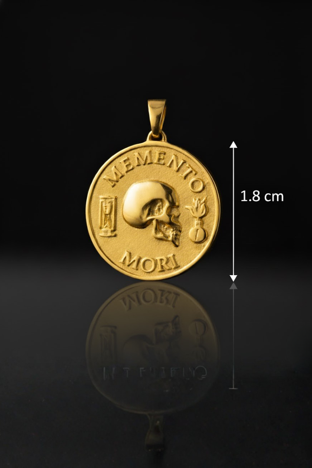 a gold-colored pendant with the inscription "MEMENTO MORI" and a skull design. The pendant is shown against a black background, and there is a measurement scale indicating its size.