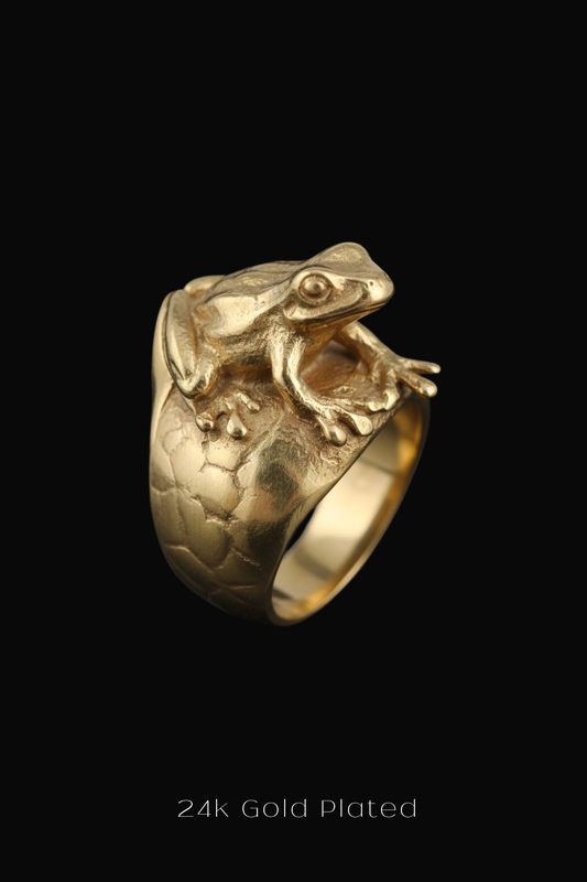 A gold ring featuring a detailed frog design on the band.