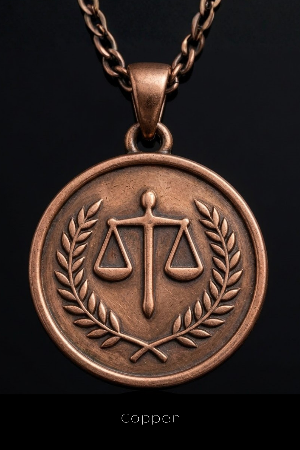 A copper-colored pendant necklace with a circular medallion featuring a balanced scale symbol and a laurel wreath.