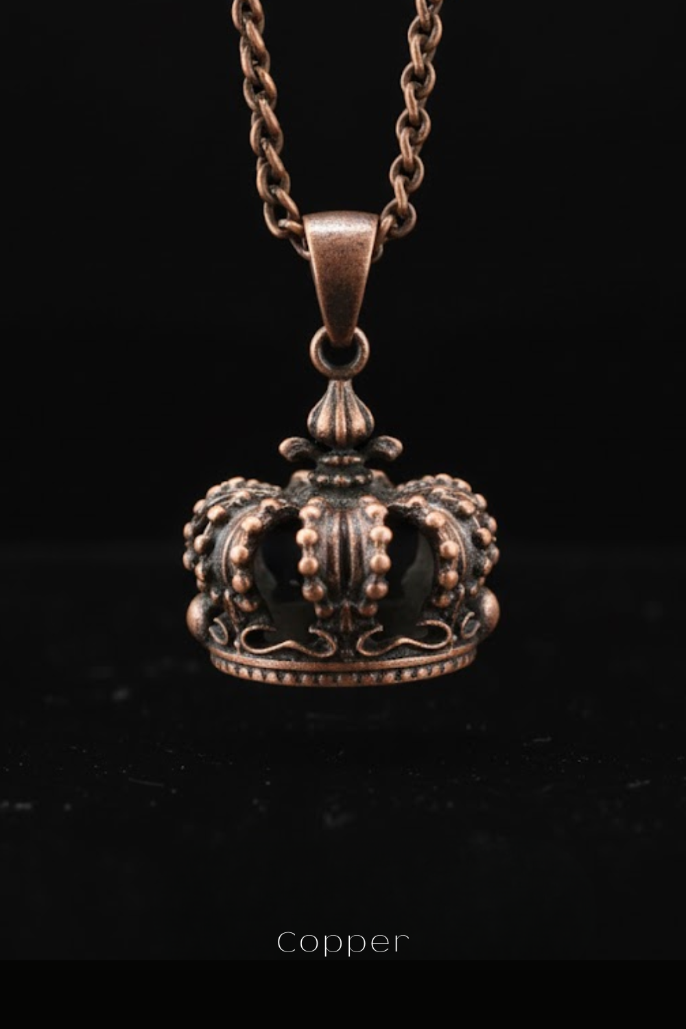 A close-up image of a copper-colored pendant necklace with an ornate crown-shaped design.