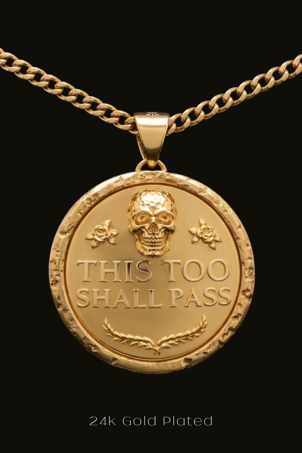 A 24k gold plated pendant with a skull design and the text "THIS TOO SHALL PASS" engraved on it.