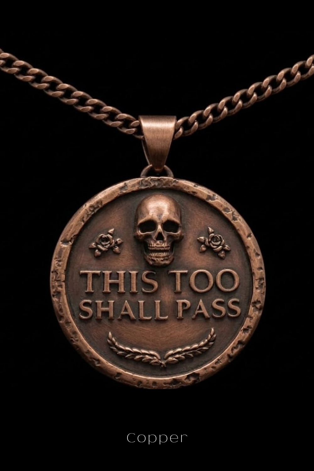 A copper-colored pendant necklace with a circular medallion featuring a skull and the text "THIS TOO SHALL PASS" in a bold, capitalized font.