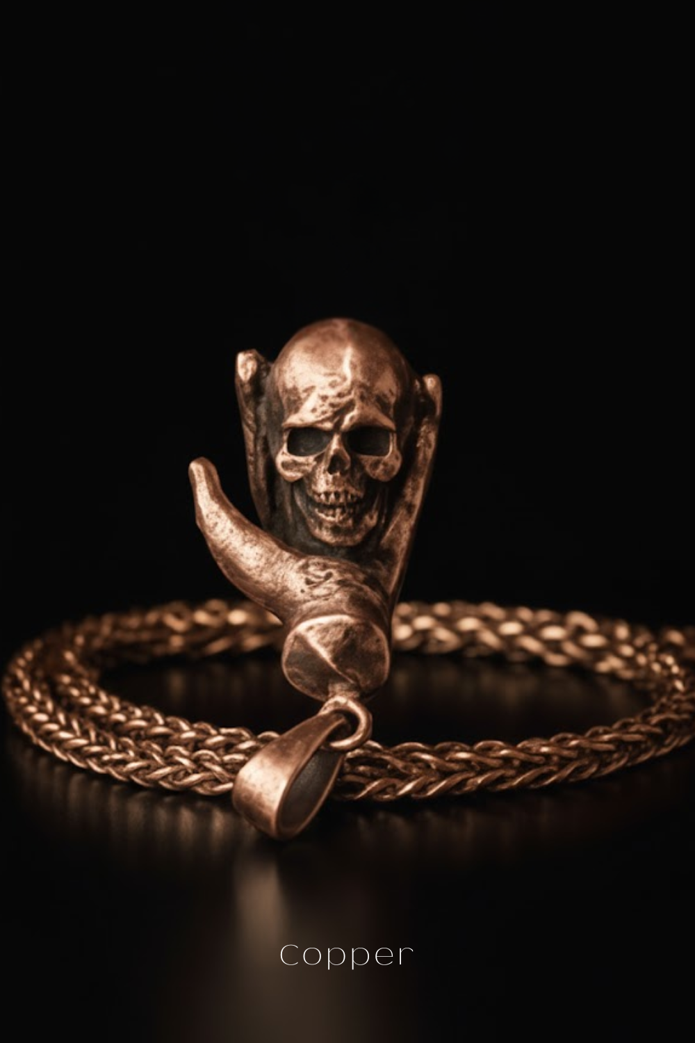 A close-up image of a bronze-colored pendant featuring a skull design, with a chain around it.