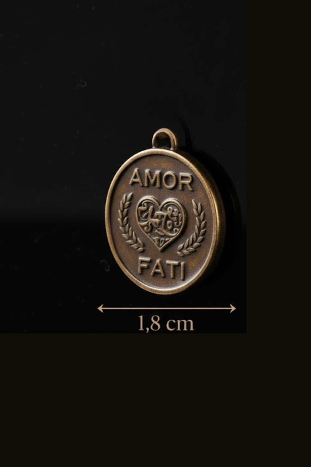 A close-up image of a round metal pendant with the text "Amor Fati" engraved on it, along with a heart symbol.