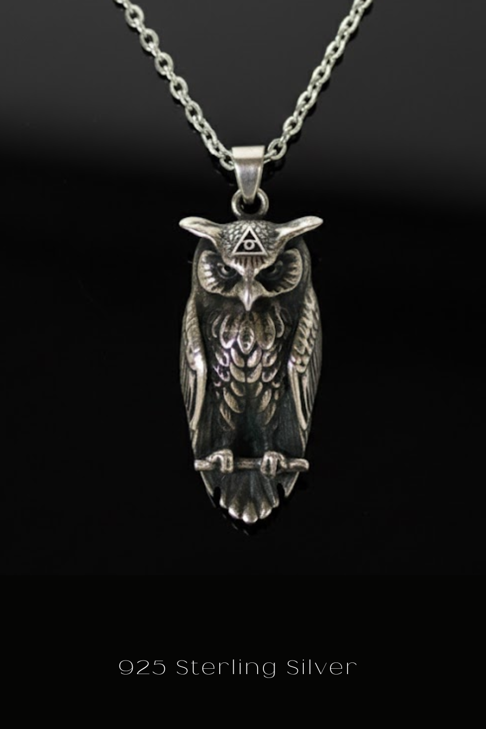 A silver pendant in the shape of an owl, with a triangular symbol above its head.