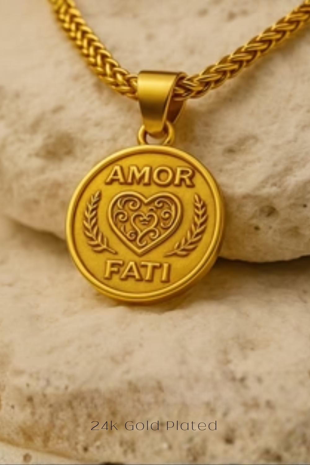 A gold-plated pendant necklace with a heart-shaped medallion featuring the words "Amor Fati" engraved on it.