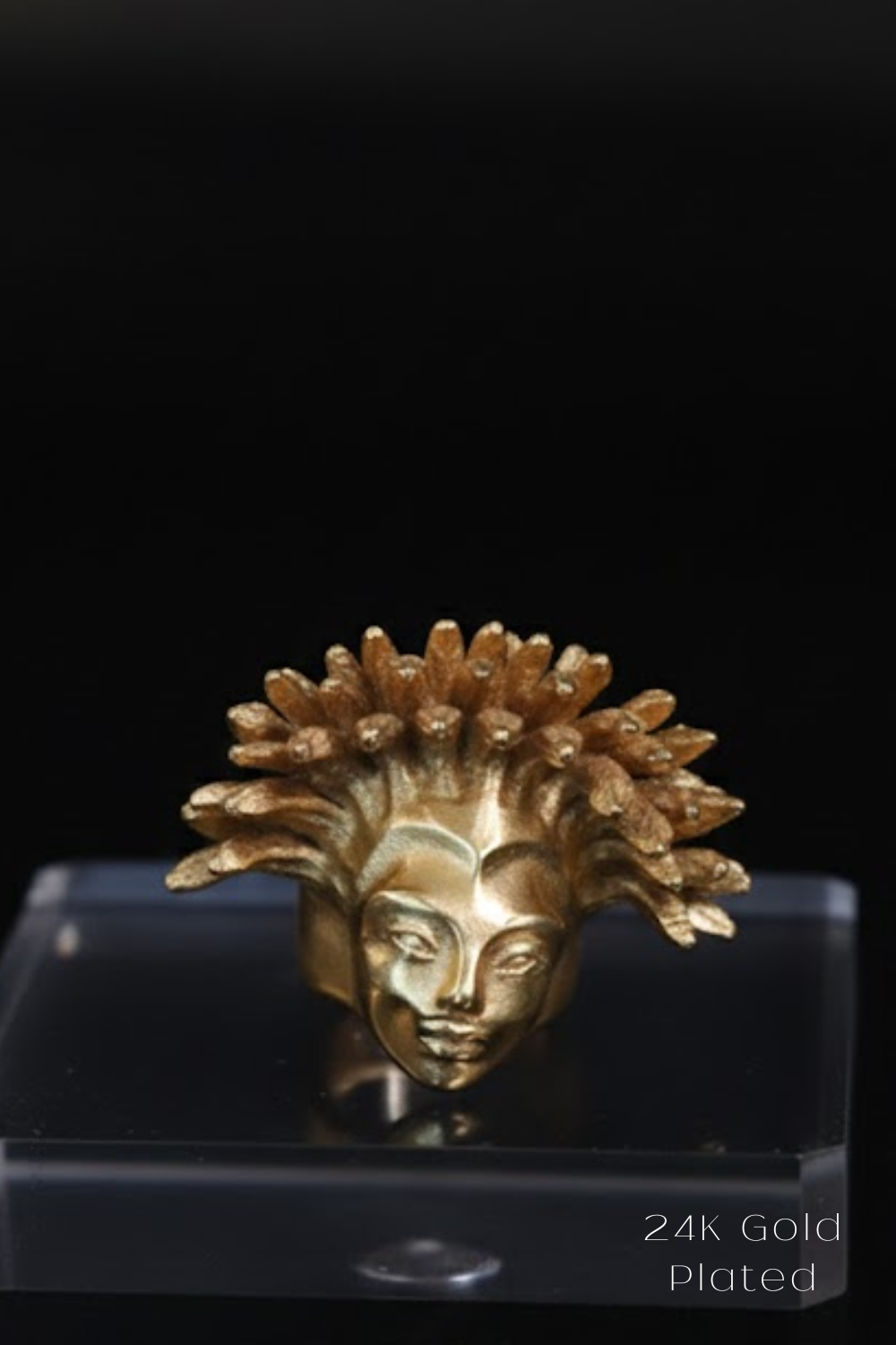 A 24K gold-plated ring in the shape of a female head with a crown-like design.