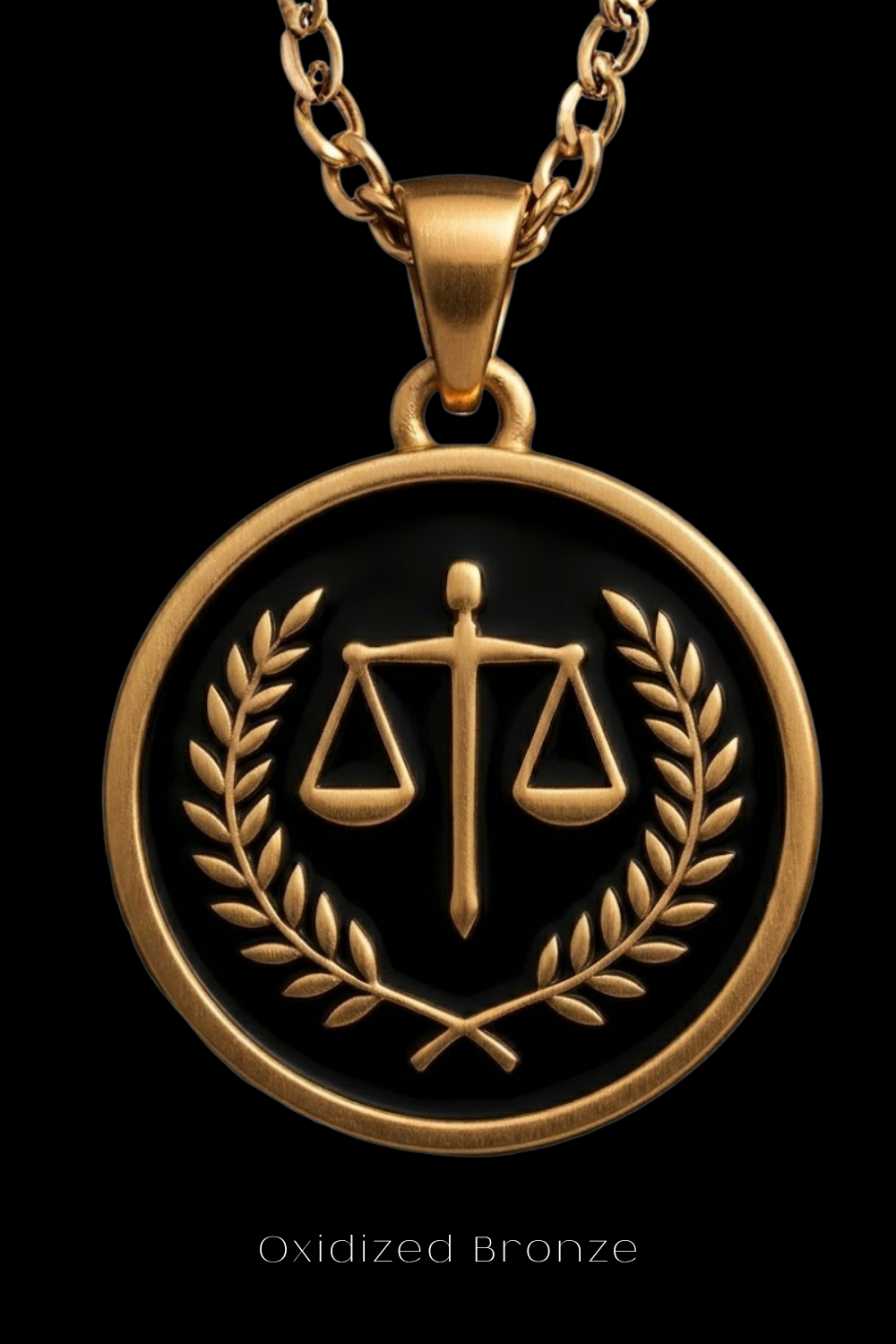 A gold-colored pendant with a circular design featuring a scale of justice symbol and laurel leaves, set against a black background.