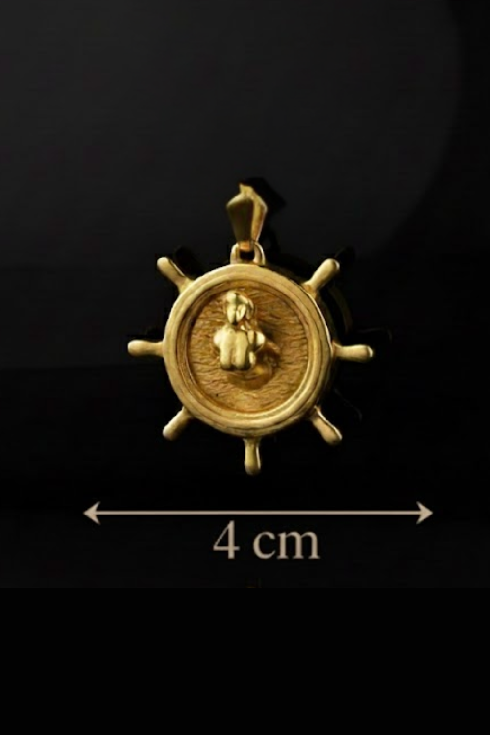 A gold-colored pendant in the shape of a ship's wheel, with a figure inside the wheel.