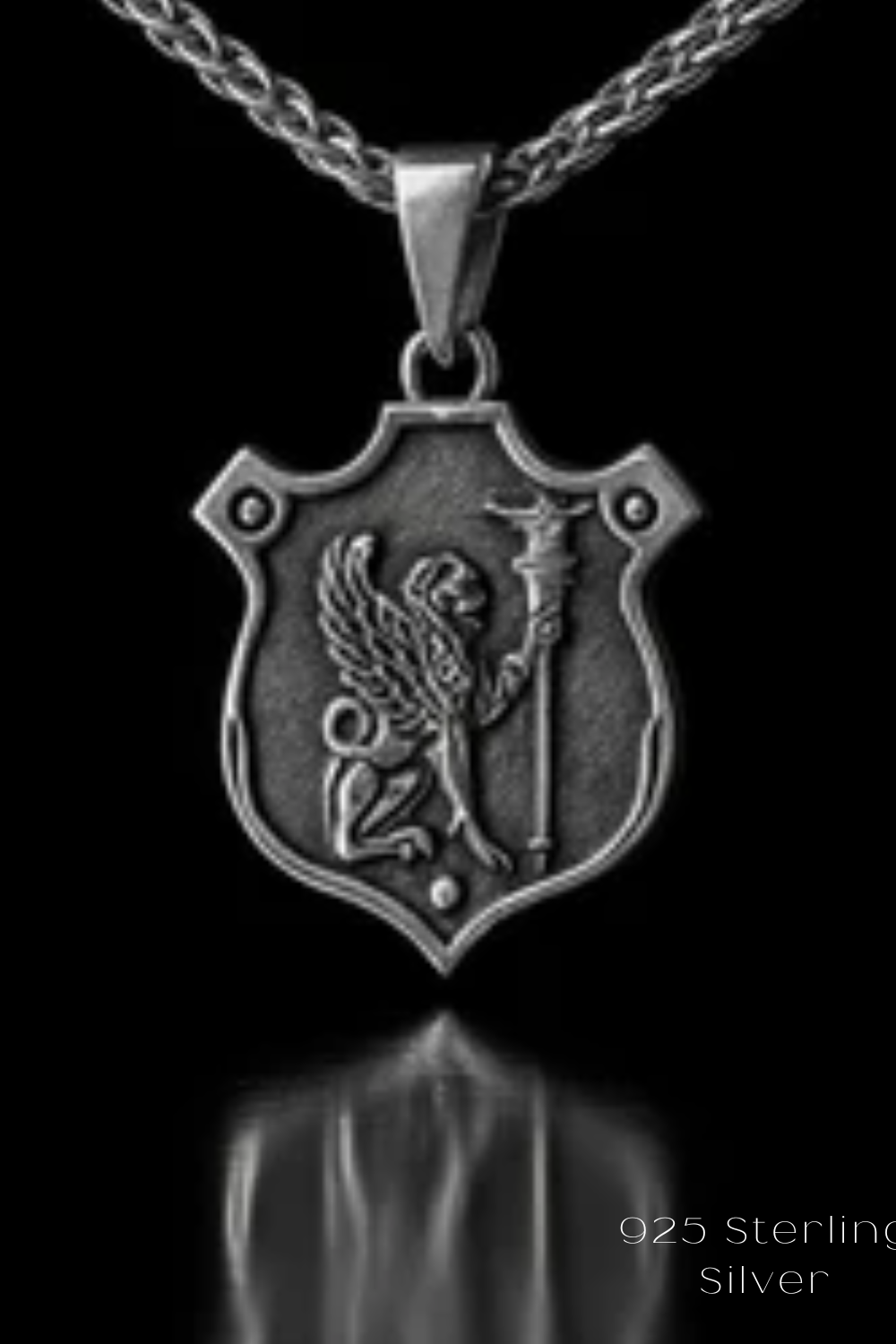 A silver-colored pendant necklace with a shield-shaped pendant featuring a winged lion or mythical creature.
