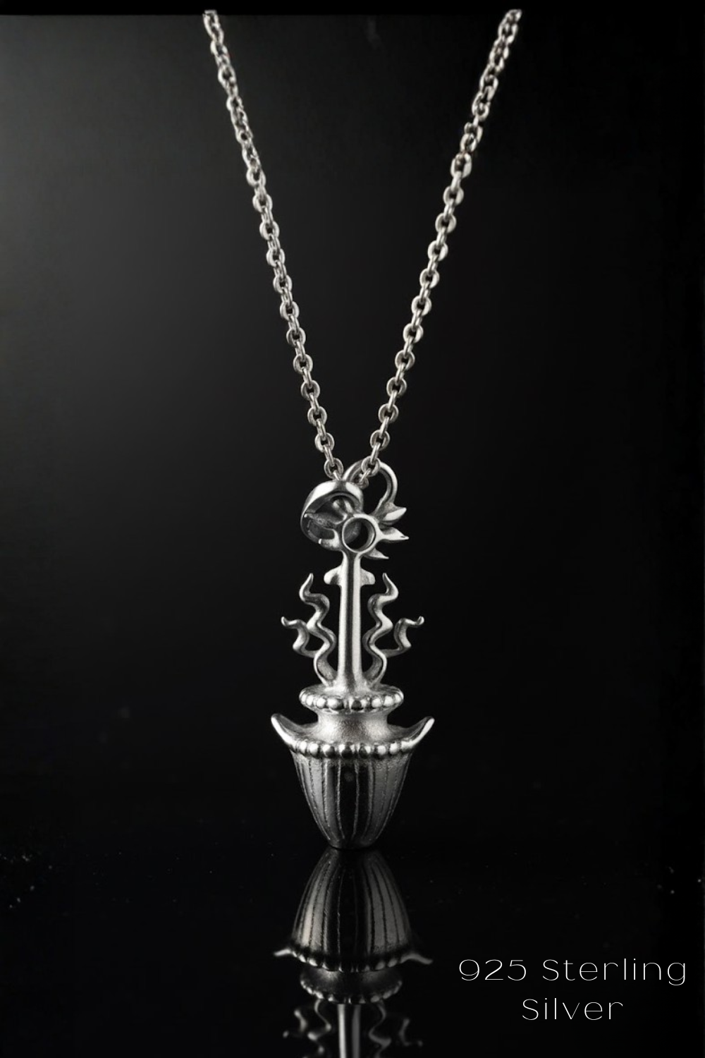 A silver necklace with a pendant featuring a stylized floral design.