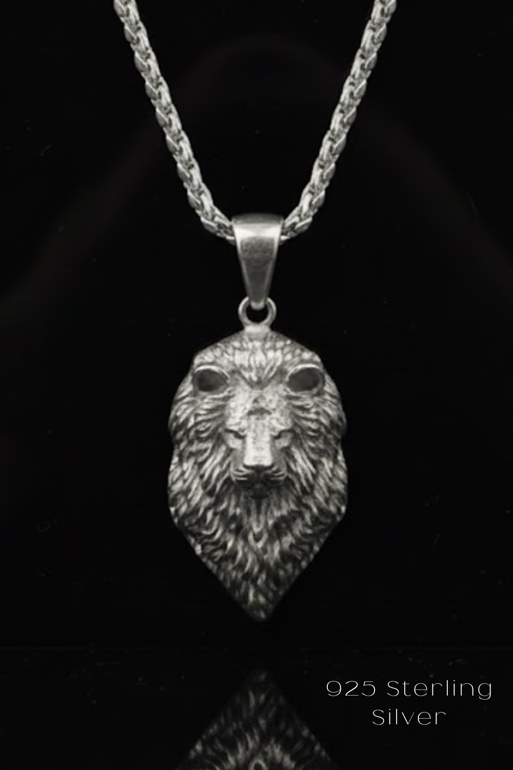 A silver pendant necklace with a detailed lion's head pendant against a black background.