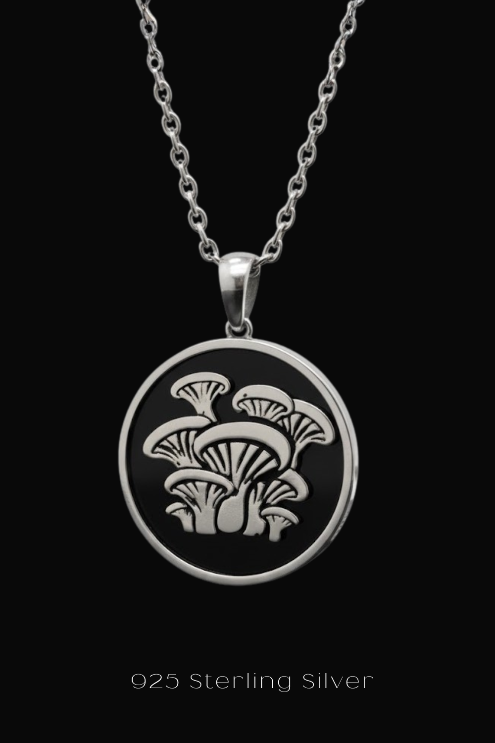 A silver pendant necklace with a circular design featuring a group of mushrooms.