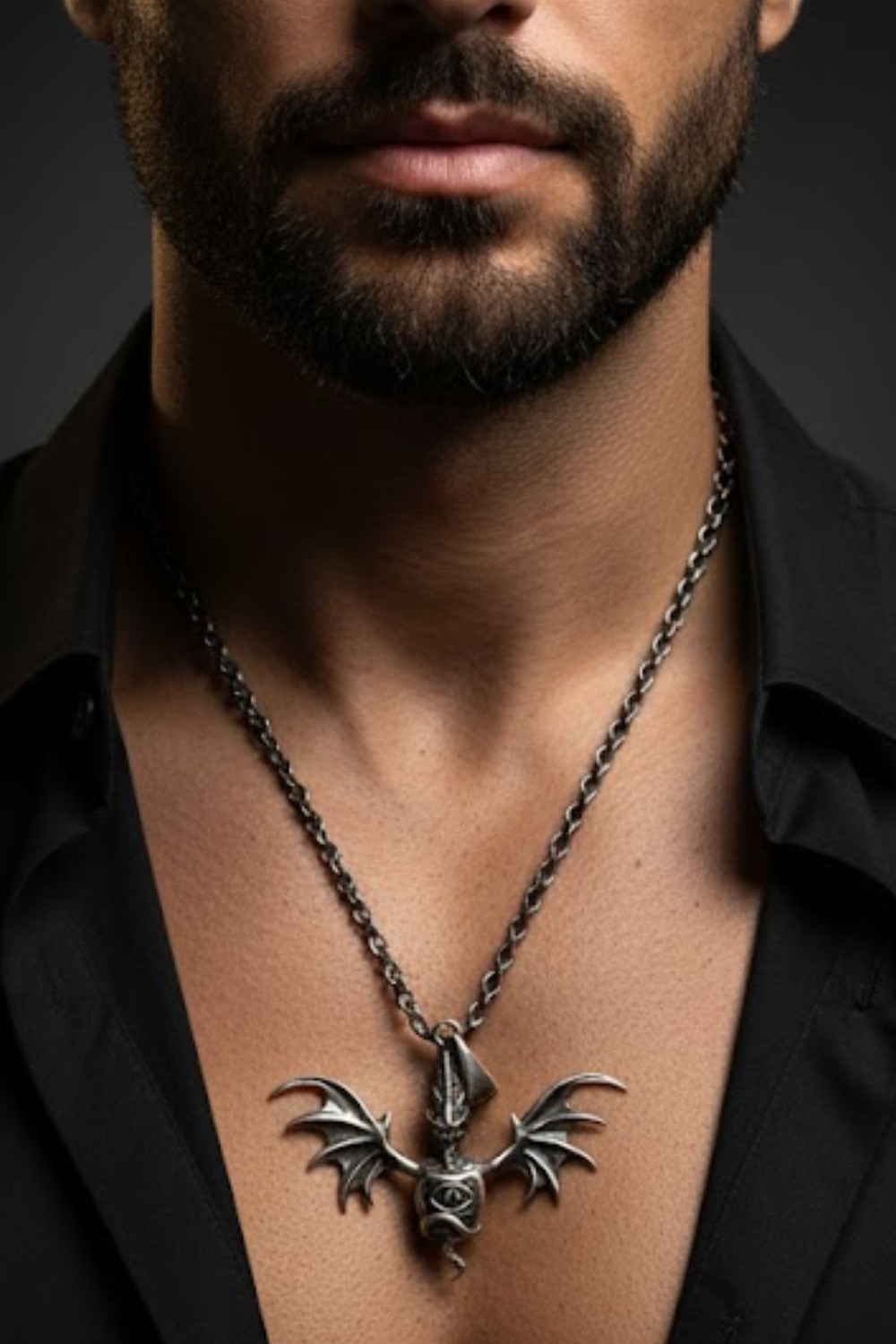A close-up of a man's neck and chest area, with a silver-colored pendant necklace featuring a winged bat design.