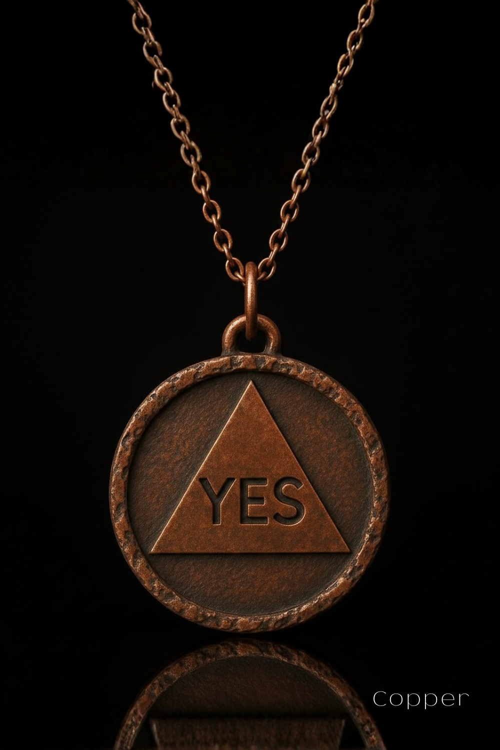 A copper-colored pendant necklace with a circular medallion featuring the word "YES" inside a triangle.
